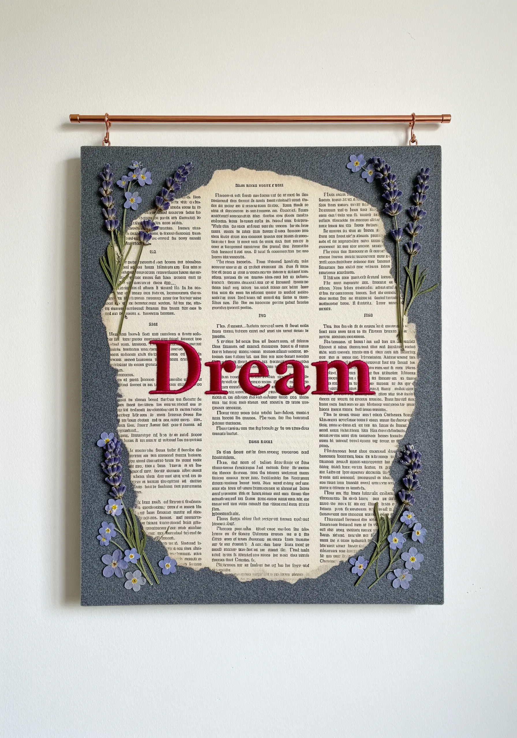 Mixed-media art with pressed lavender, an embroidered word on book pages, and a fabric background.
