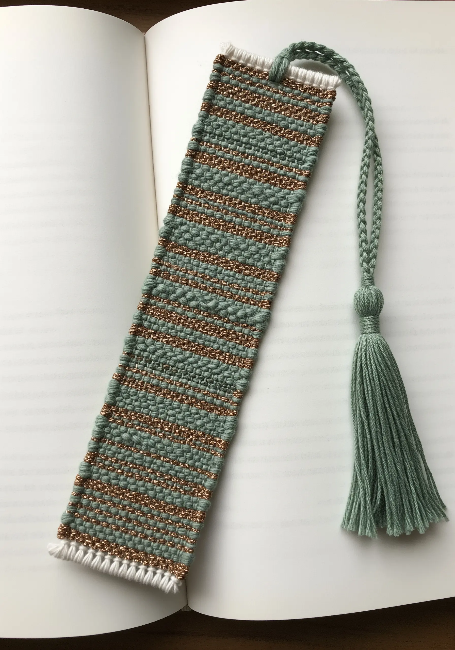 Hand-woven bookmark in sage green and metallic copper, with a matching green tassel.
