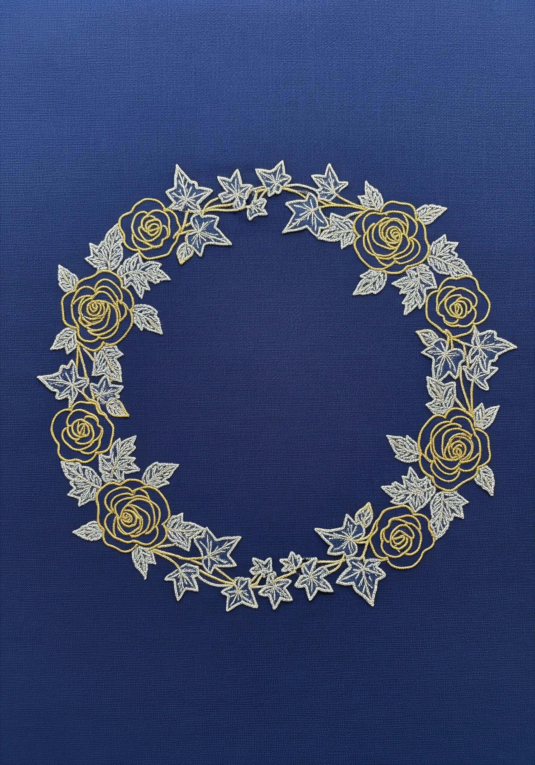 A floral wreath of roses and ivy stitched in gold and silver metallic threads on dark blue fabric.