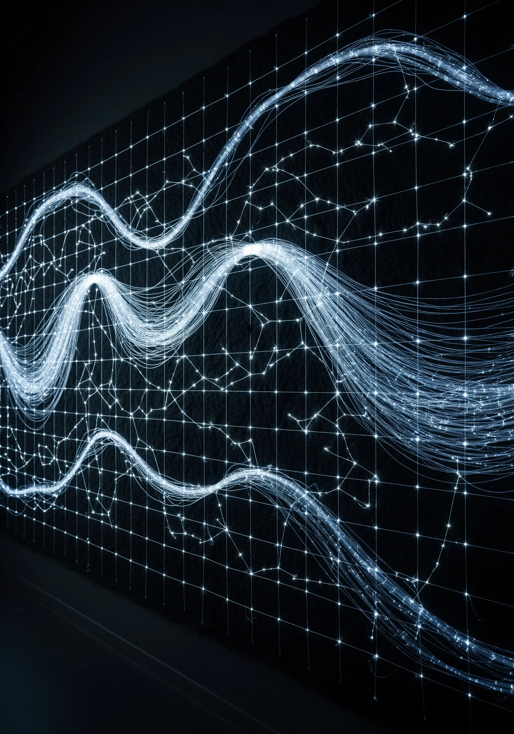 A dark wall with a grid and flowing lines of light, resembling fiber optics.