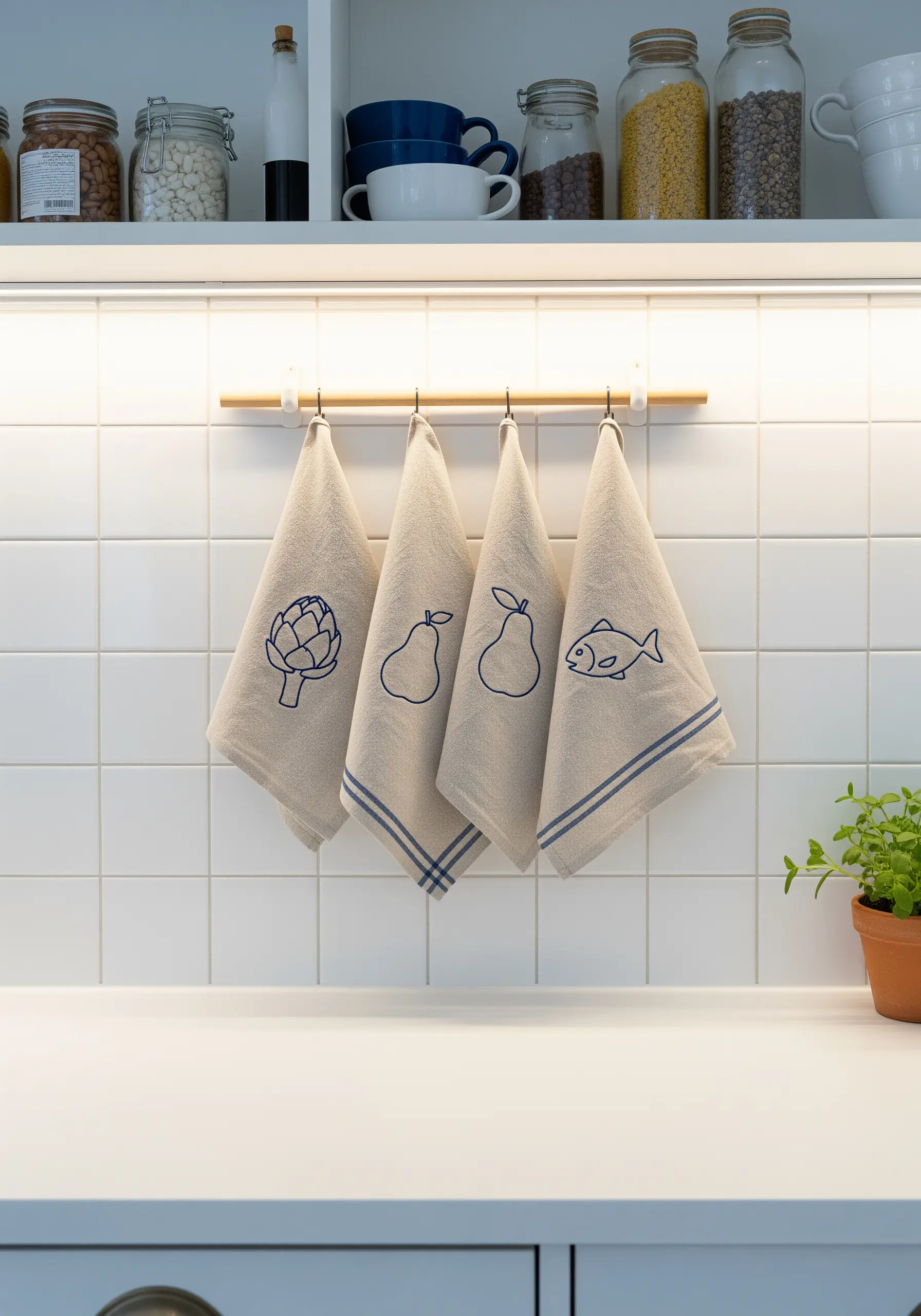 Simple line art of an artichoke, pears, and a fish on kitchen towels.