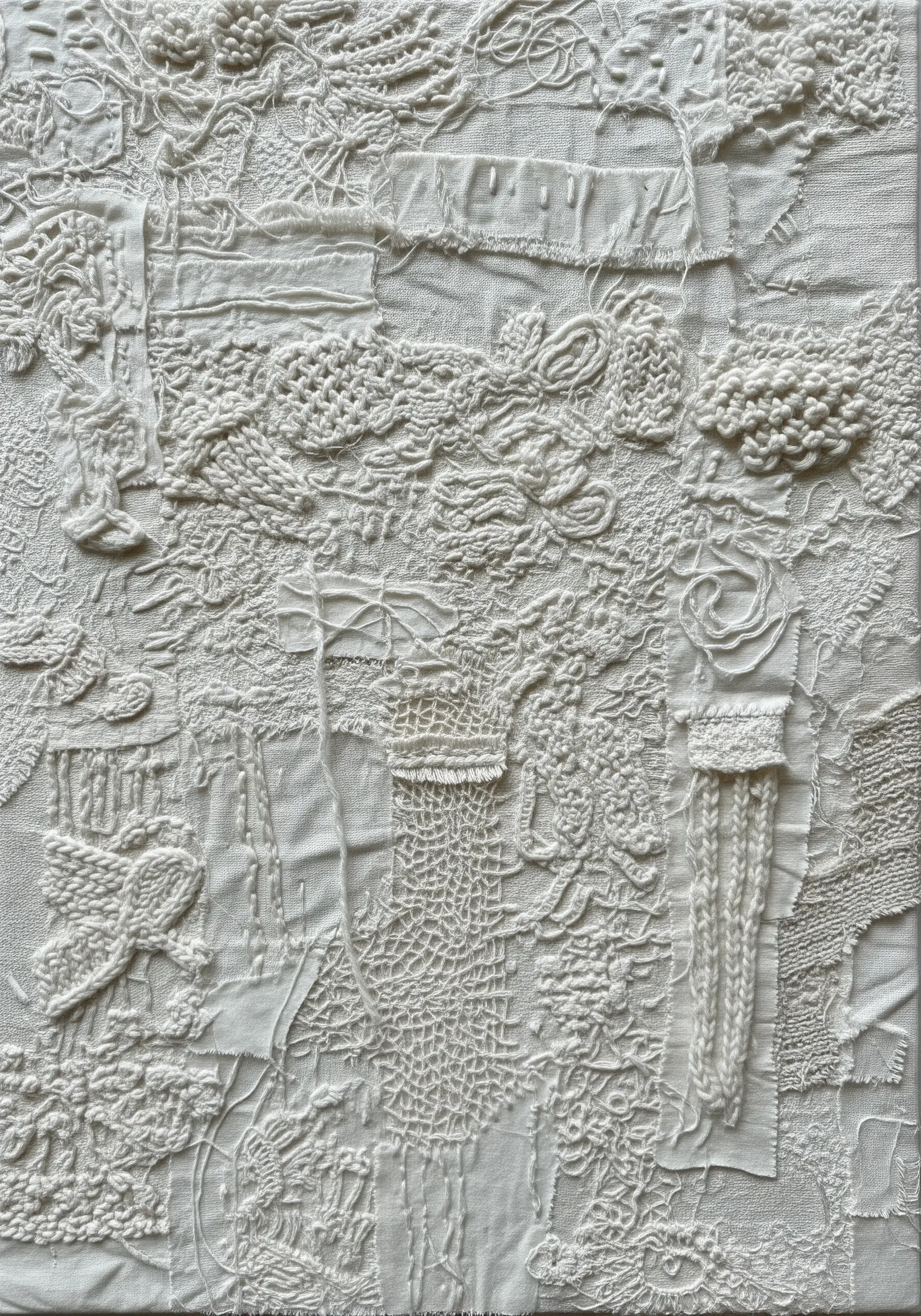 A dense, white-on-white textile collage featuring various textures like lace, canvas, and yarn.