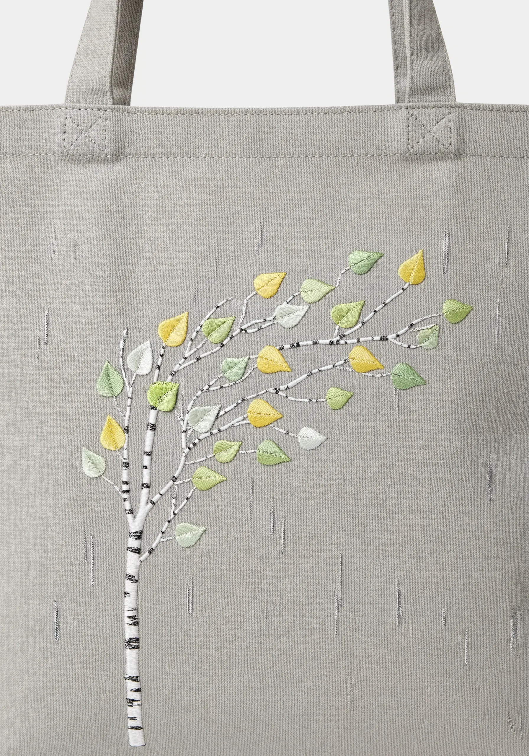 Embroidered birch tree with yellow, green, and white satin stitch leaves on a grey tote.