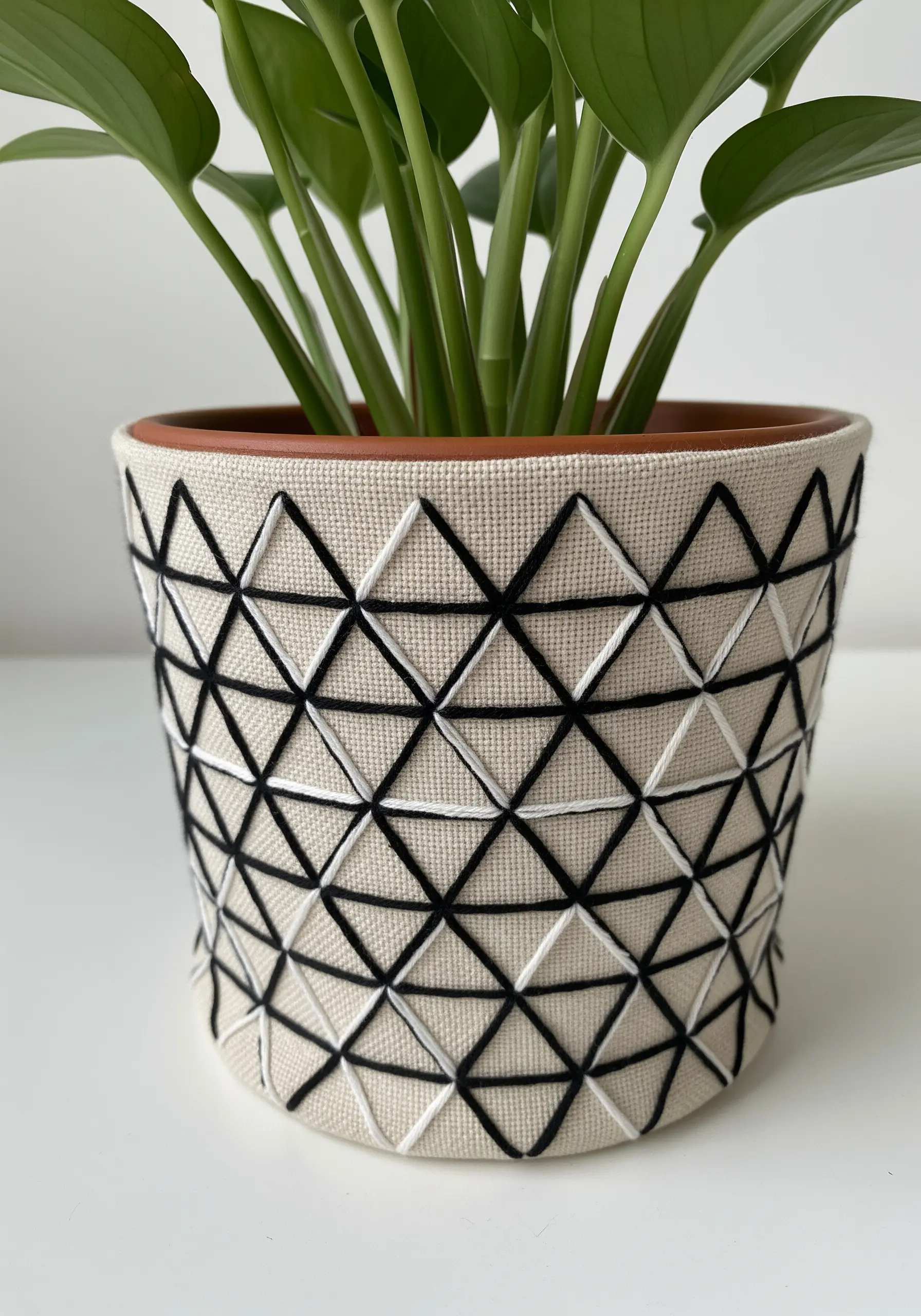 A geometric pattern of black and white triangles stitched onto a canvas plant pot cover.