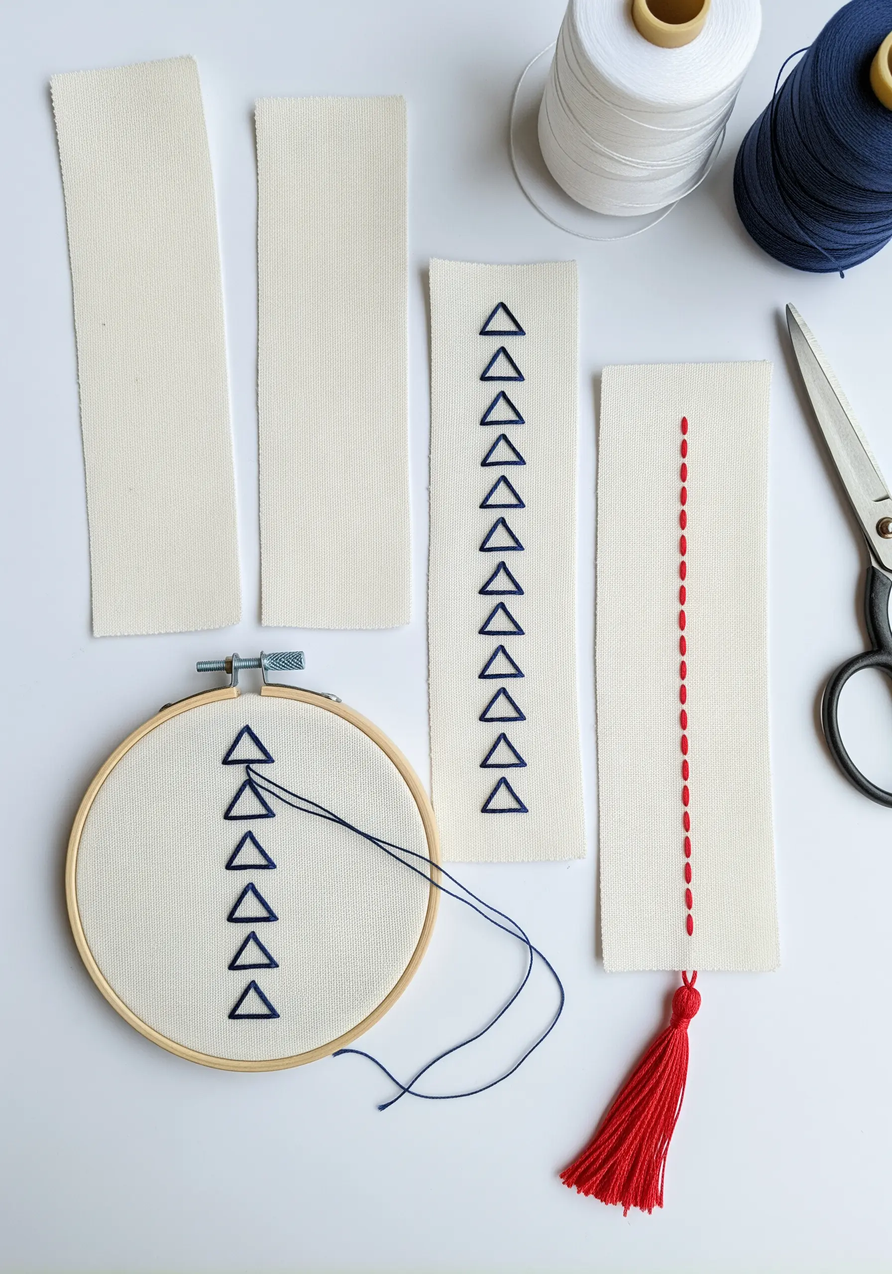 Fabric bookmarks being embroidered with repetitive geometric patterns like triangles and dashes.